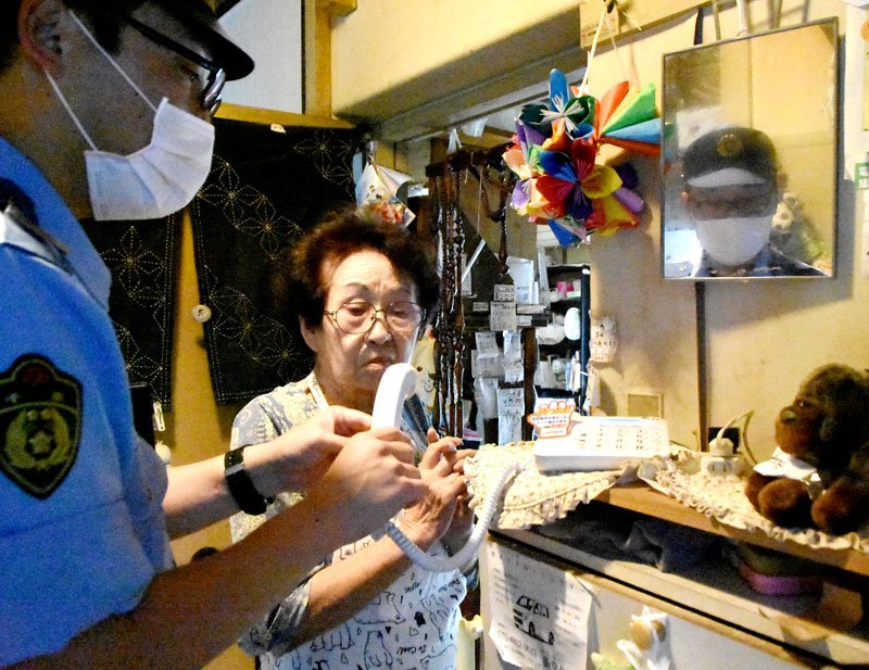 高齢者宅の固定電話機に電話de詐欺の注意喚起ステッカーを貼る千葉西署員＝６日午前、千葉市美浜区
