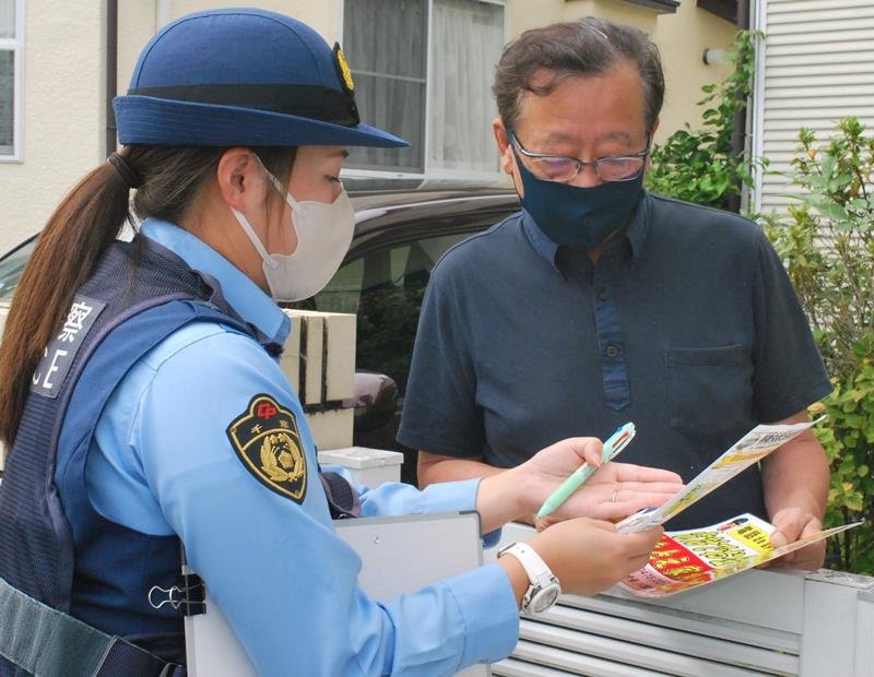 住民に啓発物を渡し、電話de詐欺への注意を呼びかける茂原署員＝１５日、茂原市

