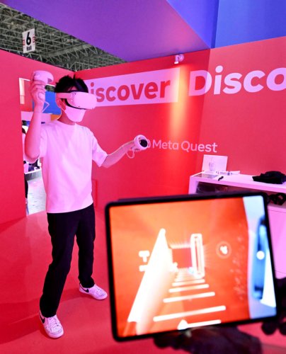 「東京ゲームショウ２０２２」の米ＩＴ大手メタのブースで、ＶＲ端末「メタ　クエスト　２」を試用する人＝１５日、千葉市の幕張メッセ（共同）