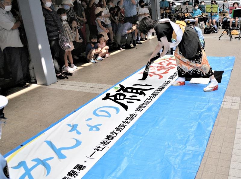 「みんなの願い交通安全」と記す横断幕を市民らの前で仕上げる矢野さん＝船橋市

