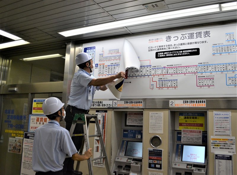 値下げ後の運賃案内板に更新する駅員＝１日午前１時過ぎ、鎌ケ谷市の北総線新鎌ケ谷駅