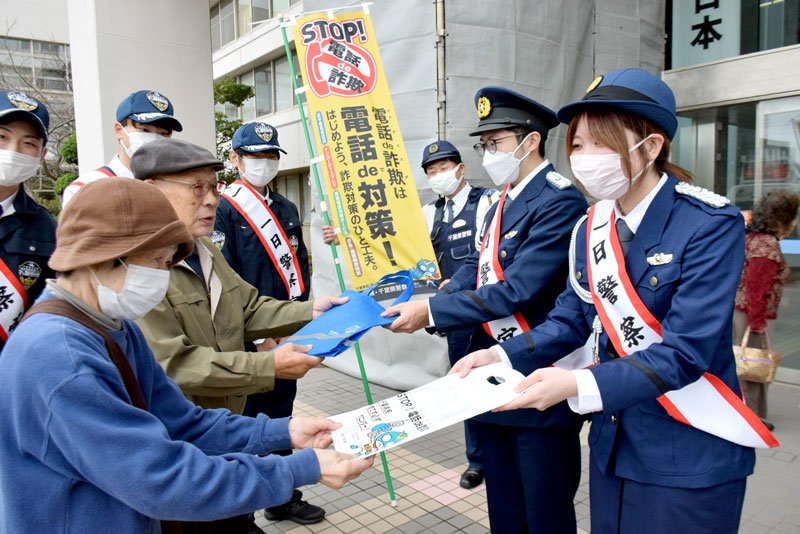 啓発グッズを手渡す一日警察官の大学生（右）＝銚子市