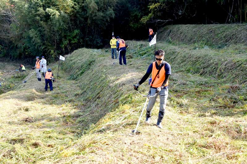 生い茂った雑草を丁寧に刈り取っていく参加者＝鴨川市
