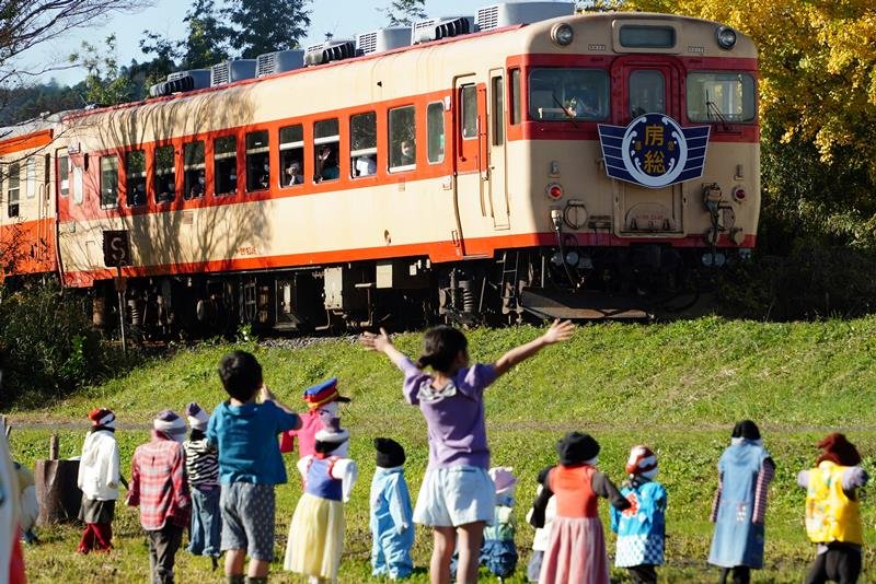 いすみ鉄道の「キハ２８」が定期運行を終了。沿線にはかかしと一緒に車両に向かって手を振る子どもの姿があった＝１１月２７日、いすみ市
