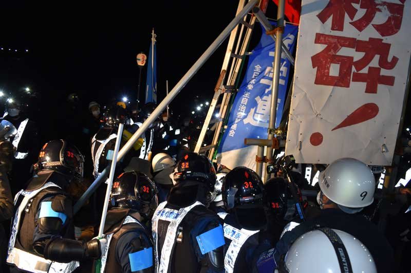 強制執行に向けて看板を取り囲む機動隊員＝１５日午後８時４０分ごろ、成田市天神峰