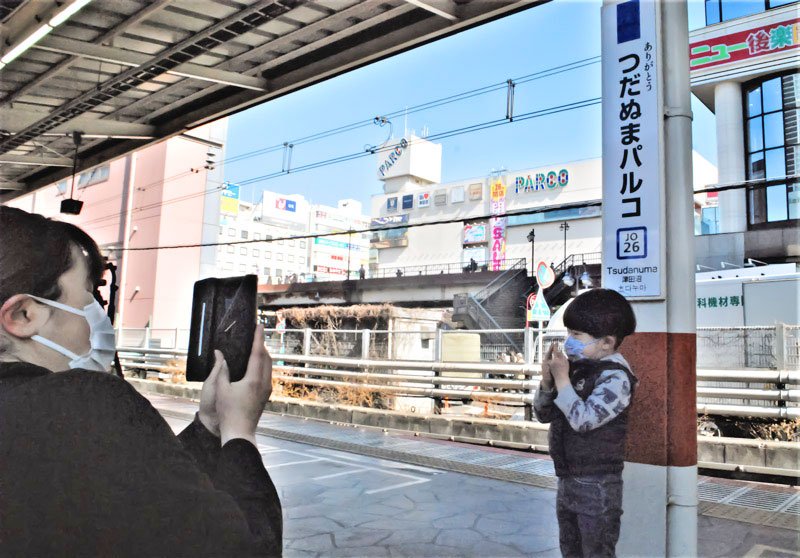 ＪＲ津田沼駅ホームに設置された「つだぬまパルコ駅」看板の前で記念撮影をする親子＝２８日午前１０時ごろ
