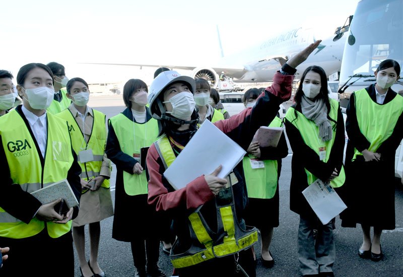 航空機が行き来する駐機場での業務について説明を受ける就活生ら＝成田空港