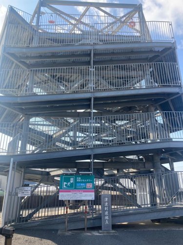 震災後に海岸部に整備された津波避難タワー。看板横は３・１１津波到達地点を伝える碑＝旭市
