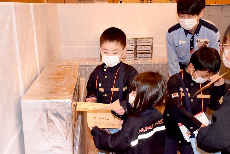 郵便局の制服姿で配達を体験する児童＝千葉市中央区