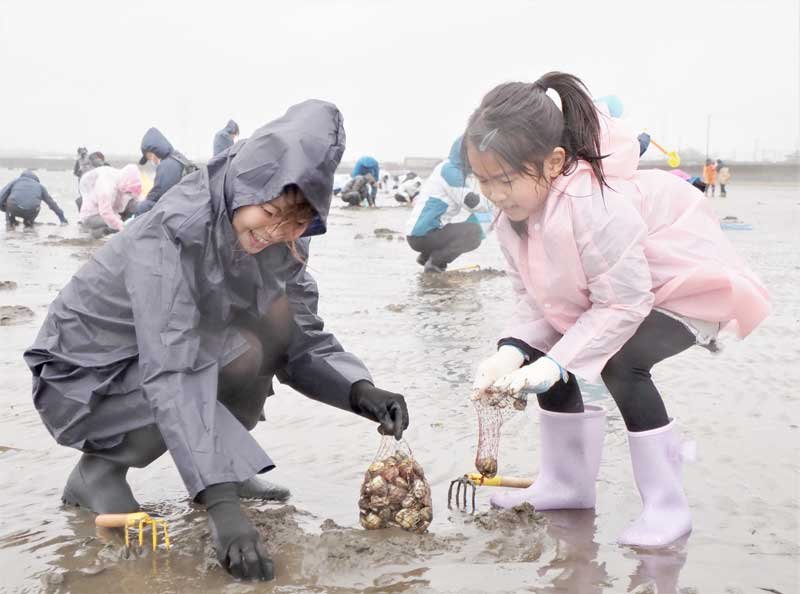 アサリやハマグリを掘り出して笑顔を見せる親子＝２５日、富津市