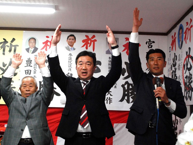 習志野市長に４選され、万歳する宮本氏（中央）＝２３日午後１１時過ぎ、同市
