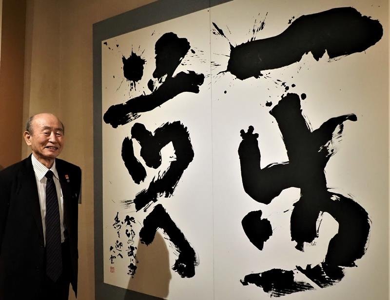 新作「一歩前へ」の横に立つ辻元さん
