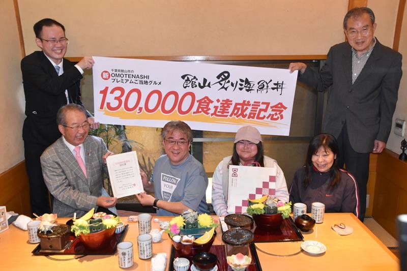 １３万食目の客となった竹内さん家族に認定書を手渡す小金会長（左）＝館山市
