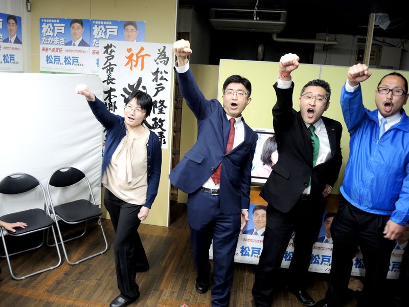拳を突き上げトップ当選を祝う松戸氏（左から２人目）＝９日午後１１時５分ごろ、松戸市の事務所