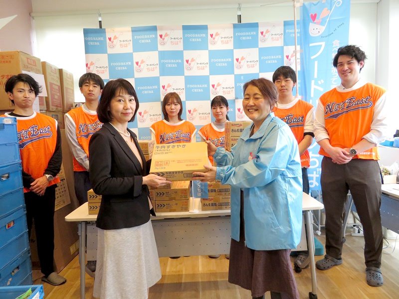 フードバンクちばの担当者に缶詰を手渡す境支店長（左）＝千葉市中央区