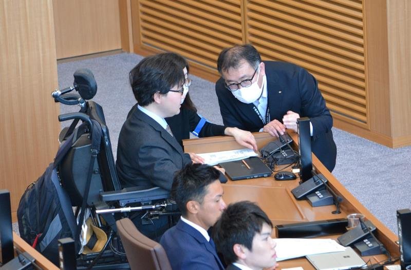 電動車いすで臨時議会に出席し、ヘルパーらの介助を受けながら正副議長選の投票を行った渡辺惟大市議（中央）＝１７日、千葉市議会本会議場
