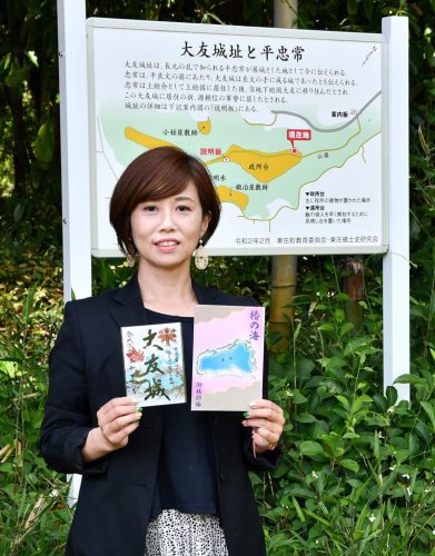 大友城の御城印と、椿の海の御城印帳を手に持つ山城ガールむつみさん＝東庄町
