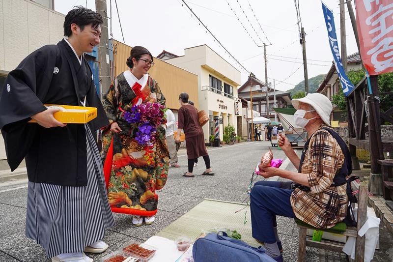 朝市出店者に結婚の報告をする（左から）吉清汐音さん、葵さん夫妻＝１８日、勝浦市

