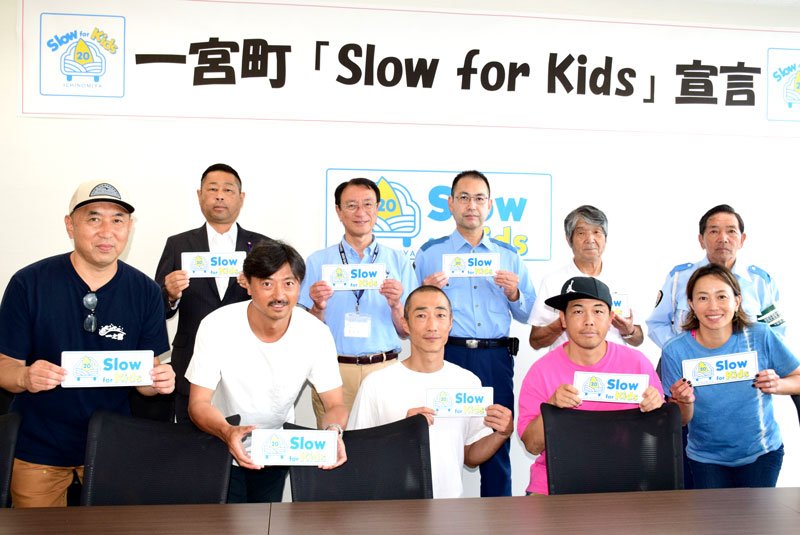 「Ｓｌｏｗ　Ｆｏｒ　Ｋｉｄｓ」と書かれたステッカーを手にする斉藤さん（前列左）ら＝２８日、一宮町役場