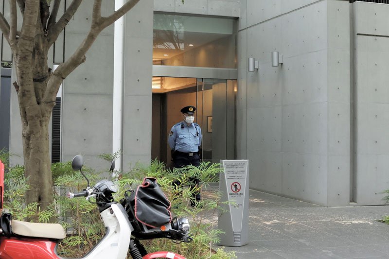 現場マンションのエントランスで警戒する警察官＝２８日午後６時ごろ、市川市