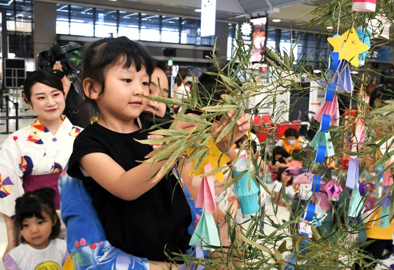 成田空港で浴衣姿のＪＡＬスタッフと一緒にササに短冊を結び付ける園児＝４日、成田市