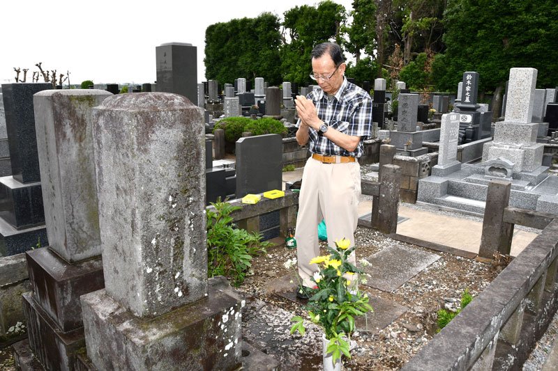 祖父の栄太郎さんが眠る吉田家の墓前で手を合わせる龍二さん＝野田市