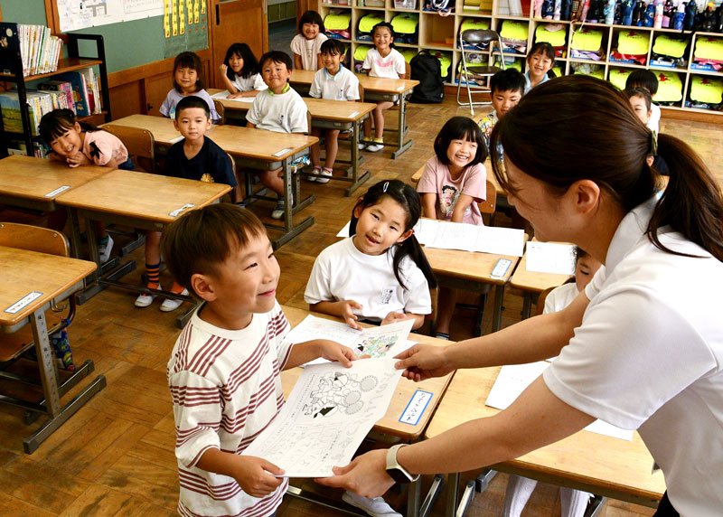 担任から夏休みのしおりを笑顔で受け取る児童＝２０日、香取市立小見川中央小学校