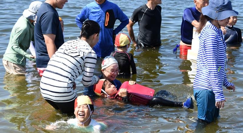 ランドセルで水に浮く体験をする子どもたち＝２３日午前、千葉市美浜区のいなげの浜