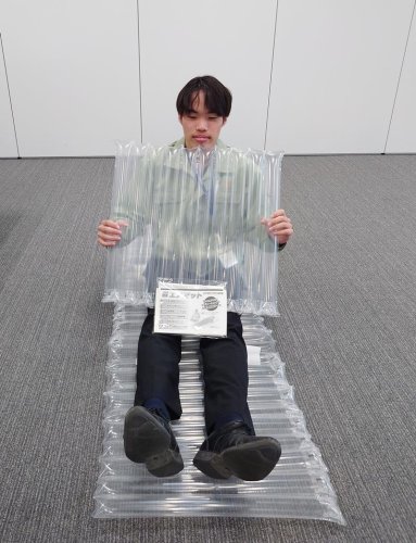 親和パッケージの緩衝材がエアマットとして使えることを実演する市原市職員＝同市役所
