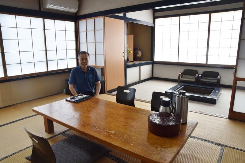 いろりがある昔ながらの客室を紹介する４代目の鈴木さん＝南房総市
