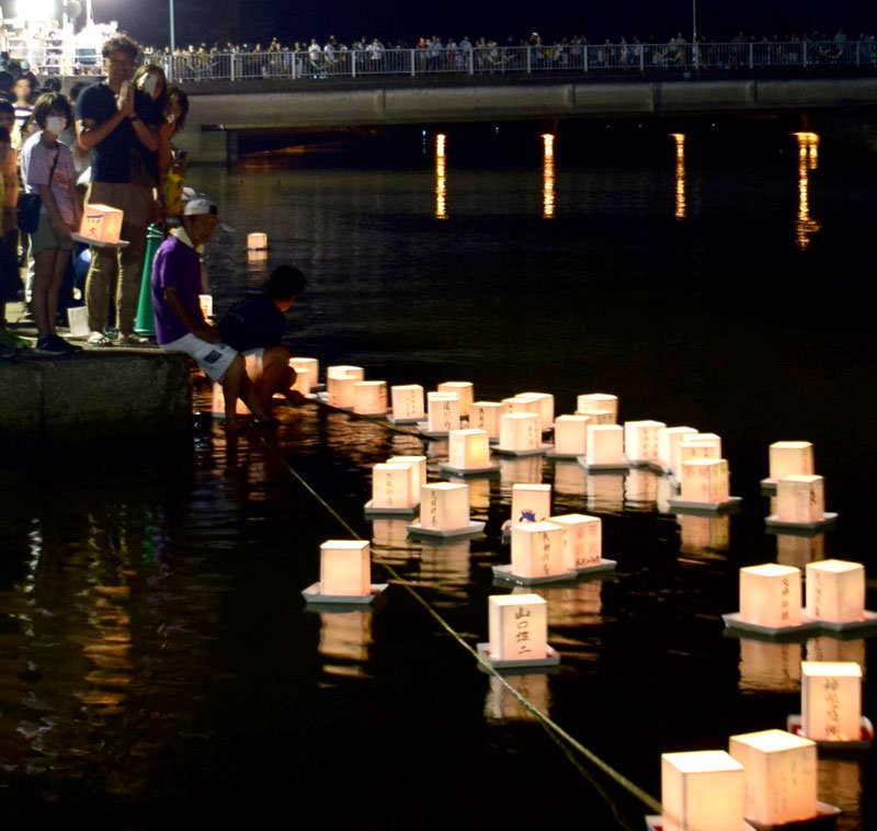 灯籠を流し手を合わせる参加者たち＝１６日夜、一宮町の一宮川