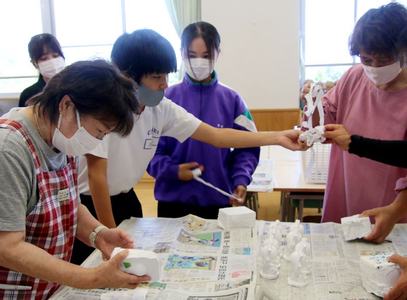 中学生とともに太陽くんの石こう像を作る地元の女性たち＝長生中（同校提供）