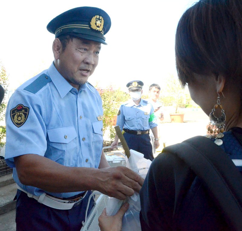 警察官の制服を着て、交通安全啓発グッズを来場者に手渡す永田選手＝東金市