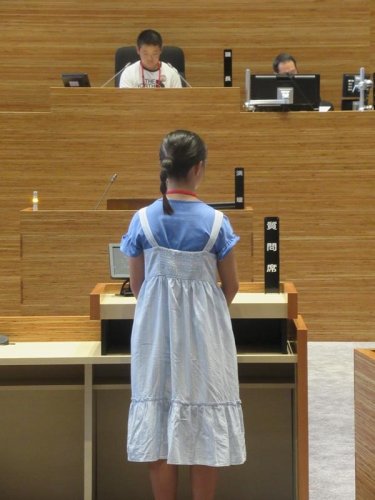 演壇で市長らに質問する「子ども議員」（手前）。奥の議長役も「同僚議員」が務める＝１９日、市川市議会議場