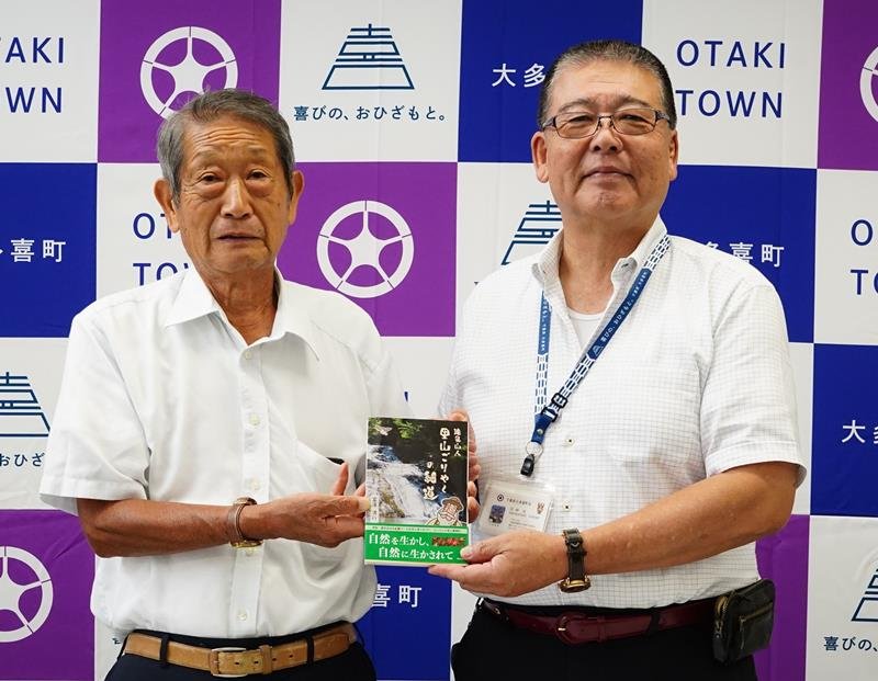 平林町長（右）へ寄贈する著書を手渡す富澤さん＝大多喜町役場
