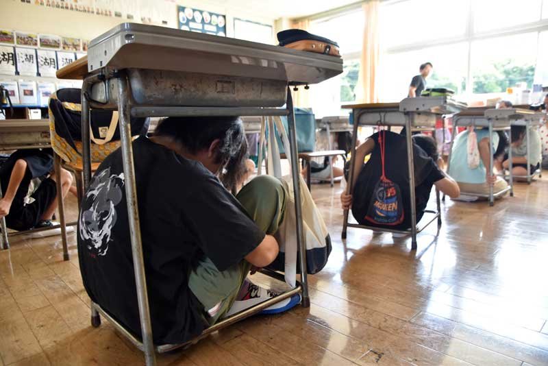 訓練で机の下に隠れ、頭を守る子供たち＝１日、館山市