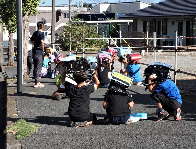 登校中、地震の発生を想定して行われた避難訓練。子どもたちは頭を保護してしゃがみ込んだ＝１日、袖ケ浦市
