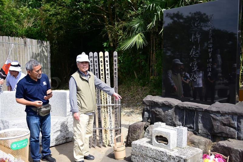 追悼慰霊碑の前で事件について語る市川さん（右）＝野田市
