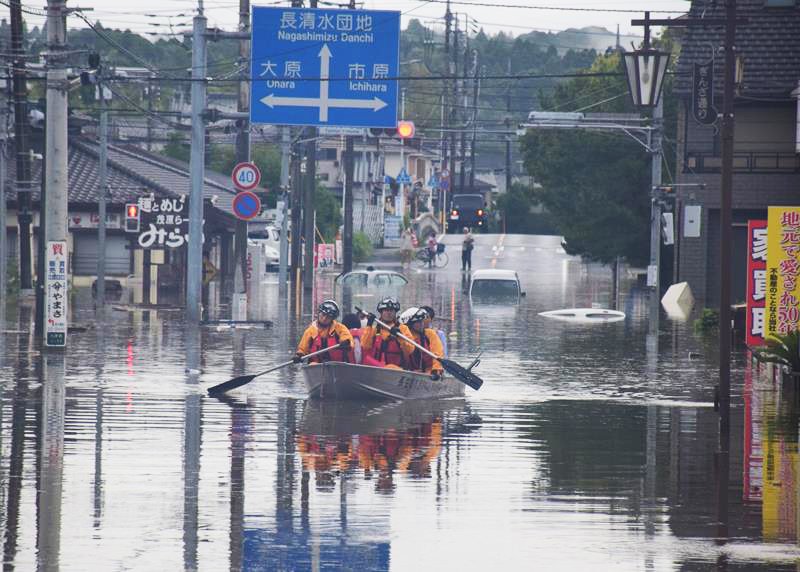 浸水した道路で救助活動をする消防のボート。胸まで水に漬かり歩く人の姿もあった＝８日午後５時５分ごろ、茂原市八千代