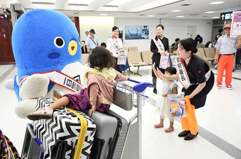 一日警察署長として成田空港の利用客に向けて交通安全を呼びかけるうなりくんとＪＡＬ社員ら＝成田市
