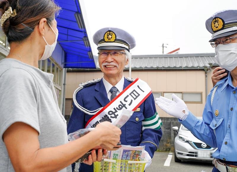 買い物客に交通安全を呼びかける柴崎さん（中央）＝２１日、御宿町