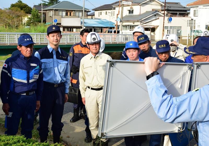 浸水地区で被災状況の説明を受ける松村祥史大臣（左）。熊谷俊人知事（左から２人目）らも同行した＝２７日午後、茂原市
