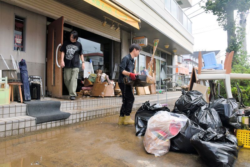 茂原市内で浸水被害を受けた店内から濡れた備品などを運び出す男性ら＝９日午前１０時２５分ごろ、同市八千代
