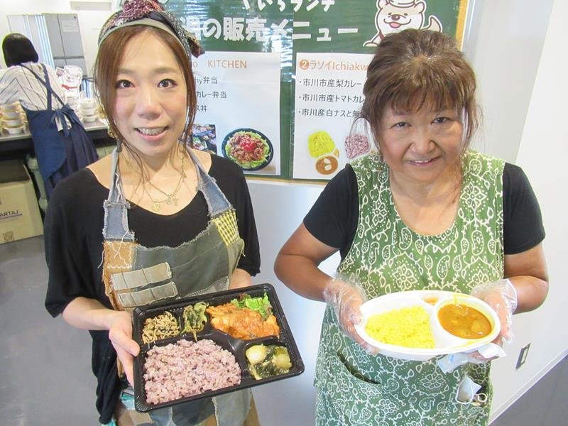 「いちランチをどうぞ」と、発酵食弁当を手にする矢路川さん（左）、地元産の梨カレーを見せる中村さん＝市川市役所
