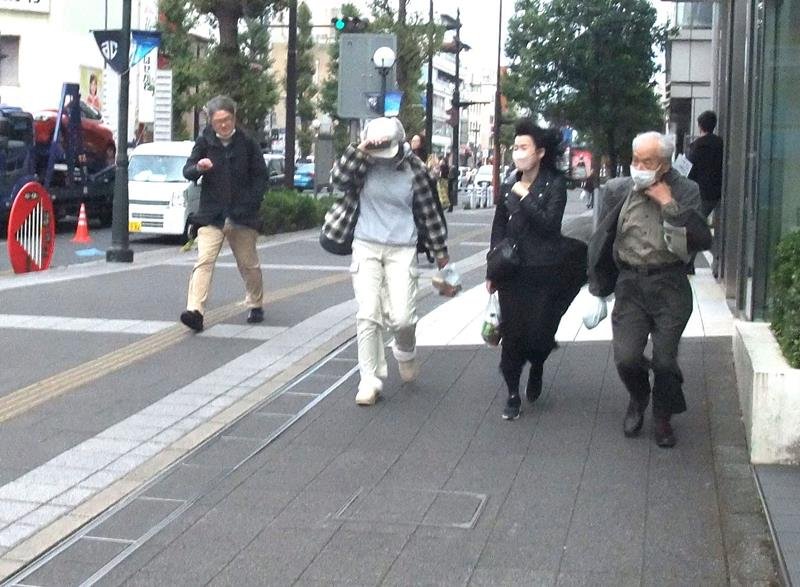 強風の中、千葉市中央区の中心部を歩く人たち＝１８日午後
