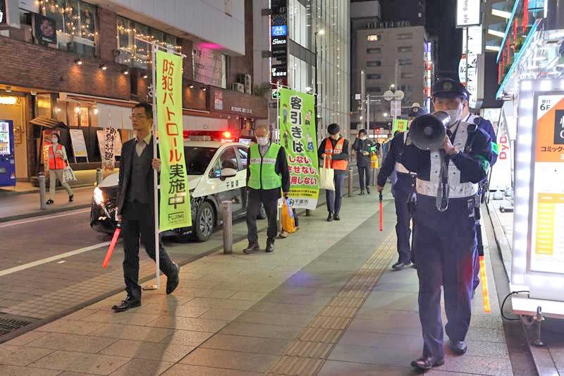 メガホンで通行人に「客引きは違法行為」と呼びかける警察官＝１１月２４日、千葉市中央区
