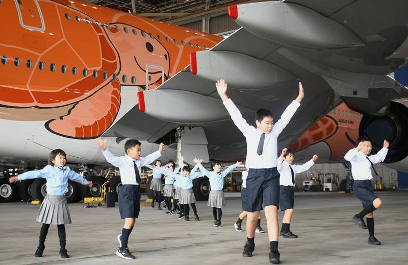 巨大な航空機の前をステージにして、はつらつと踊る子どもたち＝成田市の成田空港
