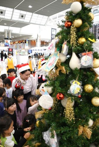成田空港に登場したクリスマスツリーに夢中になって飾り付ける園児たち＝成田市
