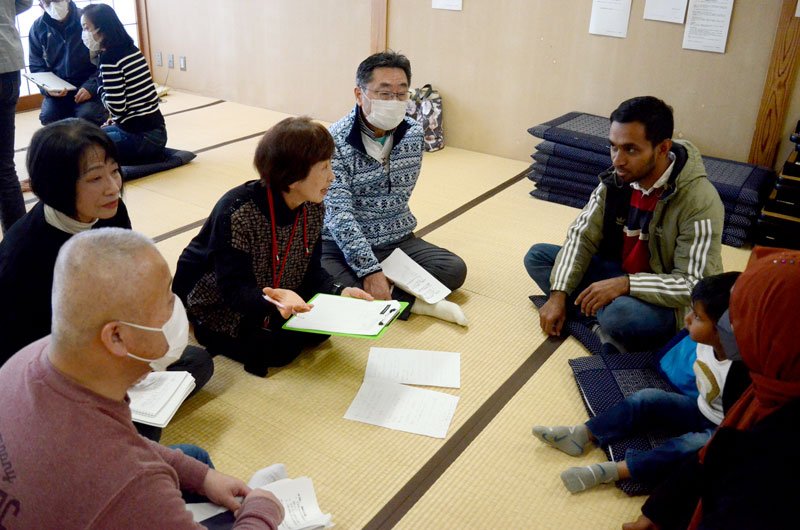 災害時の外国人支援訓練で、避難者役の外国人家族から話を聞く受講者たち＝東金市