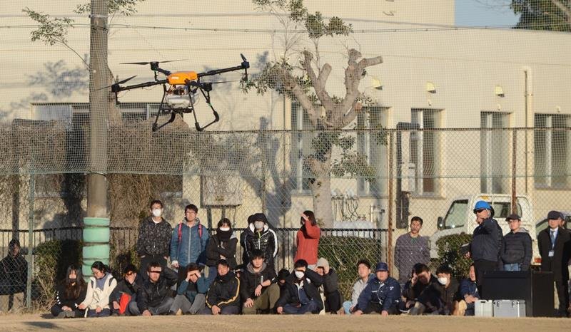 県立農業大学校の学生の前で実施された農業用ドローンの飛行実演。農薬を入れるタンクが搭載されている＝東金市
